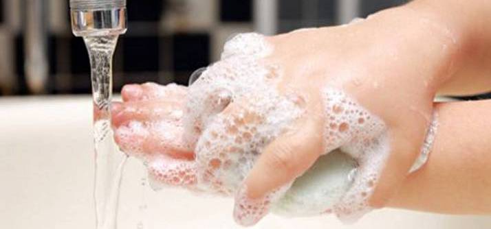 manos de niño que se está lavando las manos con agua y jabón