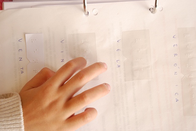 Un mano de niño/niña leyendo braille